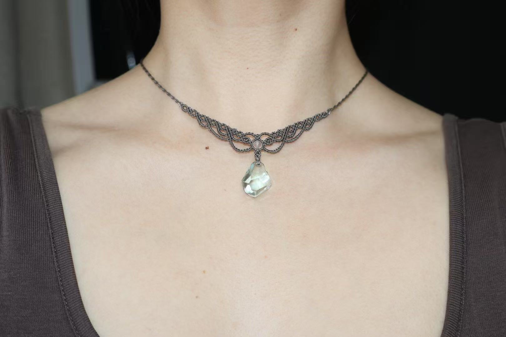 Close-up of irregular quartz crystal in hand-knotted macrame cradle, showcasing natural fractures.